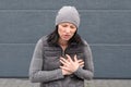 Woman in a grey winter outfit clutching her chest