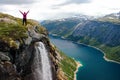 Woman standing over a mountain lake and small waterfall, Norway. Royalty Free Stock Photo