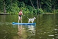 Woman standing on paddle board with her white dog Royalty Free Stock Photo