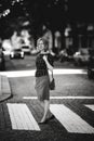 A woman is standing on a pedestrian crossing on a quiet street. Black and white photo. Royalty Free Stock Photo