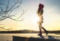 Woman standing on a pier by a lake in winter at sunset. Royalty Free Stock Photo