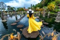 Woman standing in pond with colorful fish at Tirta Gangga Water Palace in Bali, Indonesia. Royalty Free Stock Photo