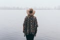 Woman standing on the river bank and looking towards autumn forest covered with morning fog Royalty Free Stock Photo