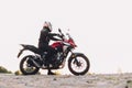 Woman standing on roadside with a motorbike. Motorcycle trip.