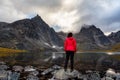 Woman Standing on a Rock at an Alpine Lake surrounded by Rugged Mountains Royalty Free Stock Photo