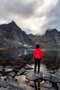 Woman Standing on a Rock at an Alpine Lake surrounded by Rugged Mountains Royalty Free Stock Photo