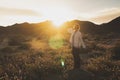 Woman standing on a rock in a wildflower field at dusk in Joshua Tree National Park California. Sunflare in photo