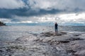 Woman standing on rocky shore with waves crashing Royalty Free Stock Photo