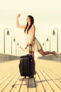 Woman standing with suitcase waving at somebody