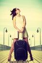 Woman standing with suitcase, windblown hair