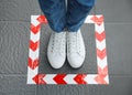 Woman standing on taped floor marking for social distance, top view. Coronavirus pandemic