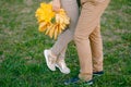 Woman is standing on tiptoe next to man, holding a wreath of yellow leaves in her hands. Legs close up Royalty Free Stock Photo