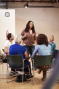 Woman Standing To Address Self Help Therapy Group Meeting In Community Center