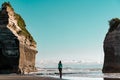 Woman standing between two big rock formations on the beach known as Royalty Free Stock Photo