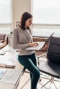 Woman standing typing on a notebook keyboard in her office