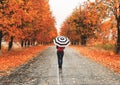 Woman standing with an umbrella on the road in autumn Royalty Free Stock Photo