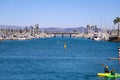 A woman standing up on paddle board rowing across the vast deep blue ocean water in the Dana Point Harbor surrounded by buoys
