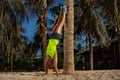 Woman standing upside down next to palm tree Royalty Free Stock Photo