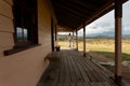 Woman standing on verandah of rural timber homestead in snowy high plains