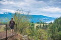 Woman standing on view platform above Fintry Falls looking at view of Okanagan Lake in FIntry Provincial Park