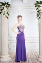 Woman standing in violet long dress nera column. Luxury interior Royalty Free Stock Photo