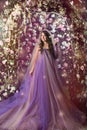 Woman standing in violet long dress under arch of pink and white roses Royalty Free Stock Photo