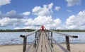 Woman standing on a wooden pier watching kids swimming.