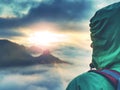 Woman stands alone on edge. Colorful mist in valley