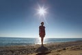 Woman stands ashore opposite sun Royalty Free Stock Photo