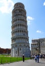 A woman stands at the base of the iconic Leaning Tower of Pisa taking a photo on her smart phone. Italy September 2017