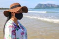 A woman stands on the beach wearing a mask to protect against the coronavirus. The concept of social distance Royalty Free Stock Photo