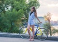 Woman stands with a bicycle on the bridge over the river in the Royalty Free Stock Photo