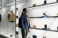 Woman stands at a boutique window and looks at shoes.