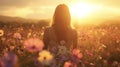 A woman stands in a field of wildflowers as the sun sets behind her creating a dreamy magical scene