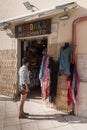 Woman stands in front of a shop selling handicrafts and clothin