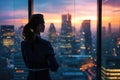 A woman stands in front of a window, gazing out at the bustling city outside, A businesswoman standing thoughtfully in her office Royalty Free Stock Photo