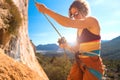 Woman stands on a large rock and belays the climber