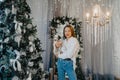 Woman stands near Christmas tree with puppy of dalmatian dog in her hands