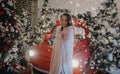 Woman stands near Christmas tree and retro car against background of snowfall Royalty Free Stock Photo