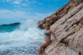 Woman stands near rocks in surf on white spray large sea waves background. Kamenovo pebble beach. Budva Riviera. Montenegro Royalty Free Stock Photo