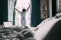 Woman stands near the window in hotel room at morning time