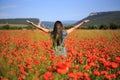 Woman stands with open arms on summer poppy field Royalty Free Stock Photo