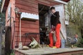 Woman stands outside chicken coop holding eggs in a basket