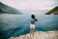 A woman stands on the pier and takes pictures of the Bay of Kotor Royalty Free Stock Photo