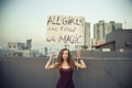 Woman stands on the roof with a poster `All girls are filled with Magic` International Womens Day concept.