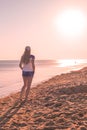 A woman stands by the sea and looks at the sunset, rear view. Travel and tourism