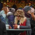 Woman stands in street cafe at the Christmas market with smartphone in her hand in Vienna, Austria