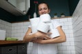 Woman stands in toilet and holds stack of toilet paper rolls in her hands.