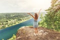 Woman stands on top of a mountain on a rock and admires the beautiful panoramic view of a river or lake in a nature reserve Royalty Free Stock Photo