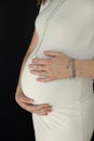 woman stands touches belly her hands Isolated black background Waiting child concept love happiness security Close-up Royalty Free Stock Photo